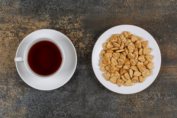 Plate of crackers and cup of tea on marble background