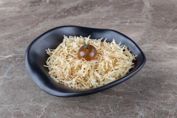 A bowl of grated pasta with tomato, on the marble background