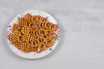 Plate of various salty crackers on stone background