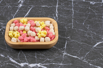 Colored cereal balls on wooden plate