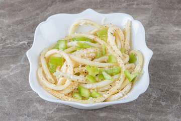 Peppered spaghetti pasta with greens on a bowl , on the marble background