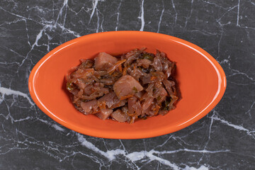 Delicious beef with chopped vegetables in orange bowl