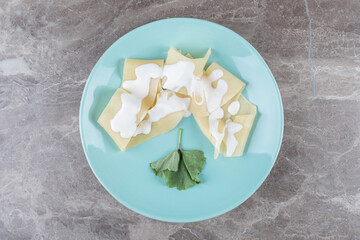 Fototapeta na wymiar Yogurt on lasagna sheets next to greens on the plate, on the marble background