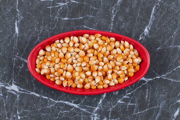 Top view of red ceramic bowl full with corn seeds