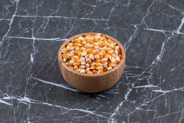 Close up photo of wooden bowl full with corn seeds