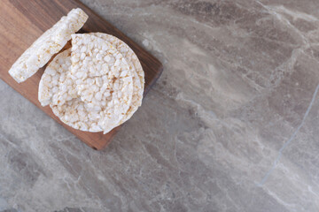 A stack of puffed rice cakes on the wooden tray, on the marble background