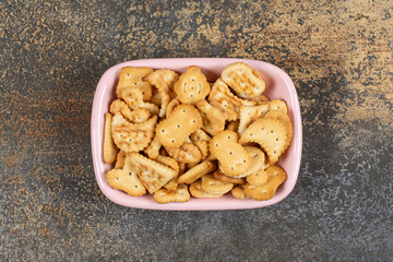 Pile of salted crackers in pink bowl