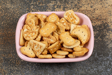Pile of salted crackers in pink bowl