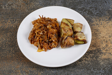 Fried eggplant rolls and onions on white plate