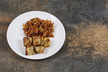 Fried eggplant rolls and onions on white plate