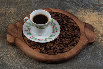 Cup of aroma espresso with coffee beans on wooden board