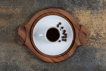 Cup of espresso with coffee beans on wooden board