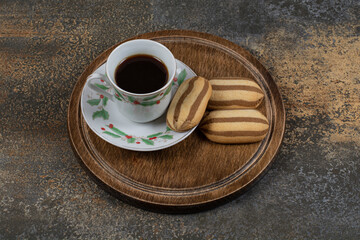 Cup of black coffee with biscuits on marble background