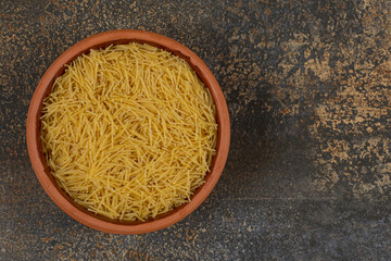 Bowl of raw macaroni on marble background