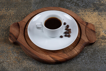 Cup of espresso with coffee beans on wooden board
