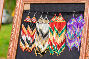 Colorful beaded earrings in boho style - handmade folk style jewelry at souvenir stall, flea market or street market. Selective focus