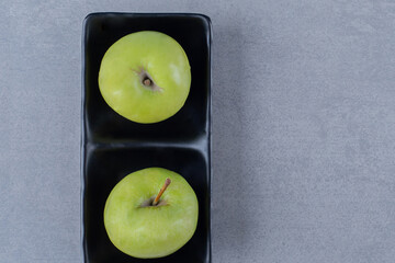 Top up photo of fresh green apple on black plate over grey background