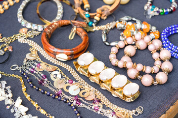 Vintage old-fashioned jewelry at flea market stall or car boot sale. Retro style bracelets and necklaces. Vintage goods for sale. Garage sale concept. Selective focus