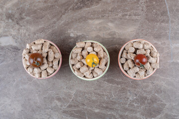 Three tomato on the bread crumbs in the bowl next to spike , on the marble background