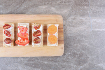 Sliced carrots and tomatoes on crispy breads , on the marble background