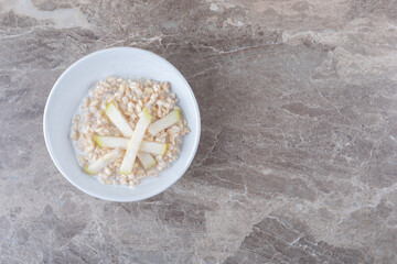 Sliced potato on a plate of rice, on the marble background