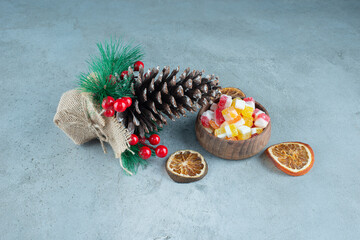 A Christmas pinecone with dried oranges and a wooden bowl of candies