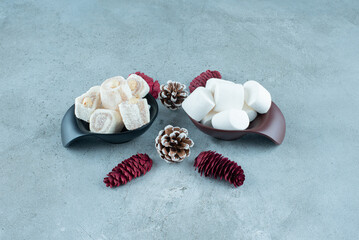 Sweet white marshmallows with pinecones on a marble background