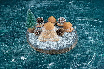 A wooden dark board with cupcakes and pinecones powdered with sugar