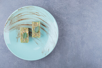 Top view of Turkish delight rahat lokum with hazelnuts on blue plate over grey background