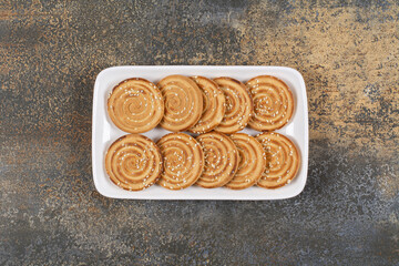 Tasty biscuits with sesame seeds on white plate