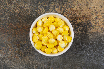 Delicious yellow candies in white bowl