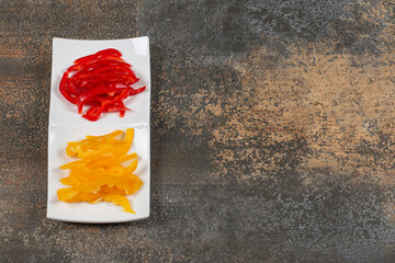 Sliced red and yellow peppers on white plate