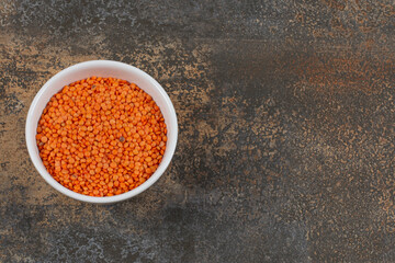 Raw red lentils in white bowl