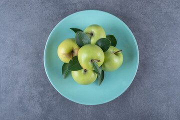 Top view of fresh organic green apples on blue plate. centered