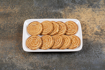 Tasty biscuits with sesame seeds on white plate