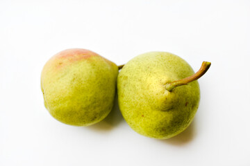 Two green ripe pears on a white background in autumn. Two fruits of a green pear in close-up.