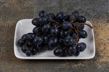 Cluster of black grapes on white plate