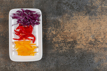 Set of sliced red and yellow peppers, purple cabbage on white plate