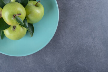 Top view of fresh organic green apples on blue plate