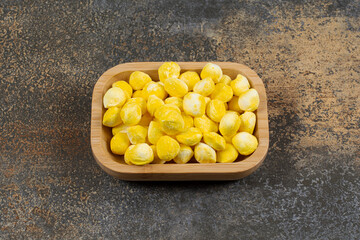 Yummy yellow candies on wooden plate