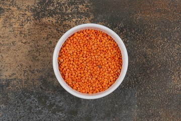 Raw red lentils in white bowl