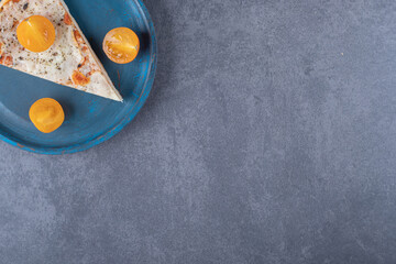 Top view of margarita pizza slice with tomato on blue wooden plate
