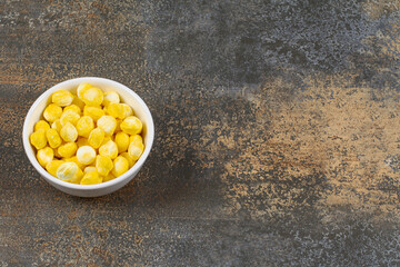 Delicious yellow candies in white bowl