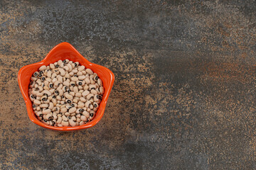 Heap of dry white beans in orange bowl
