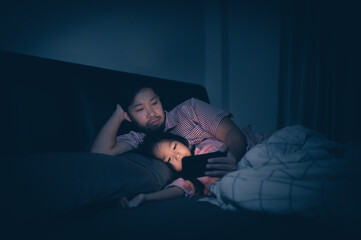 Fototapeta na wymiar Dad and daughter sleep on the bed in bedroom,Watch cartoon with phone,Father day concept,Single dad,listen tale before sleep