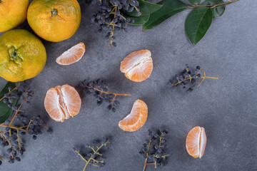 Fresh organic tangerines and slices on grey background