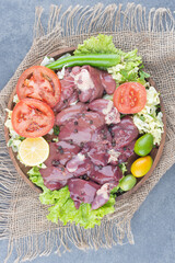 Raw meat pieces and vegetables on wooden plate