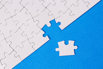 Missing jigsaw puzzle pieces. Business concept. Fragment of a folded white jigsaw puzzle and a pile of uncombed puzzle elements against
