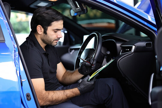 Portrait of an Auto Service Technician holds a pre-delivery inspection checklist for physical and interior inspection that the car repair shop.