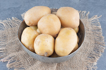 Bunch of potatoes in metal mug with burlap